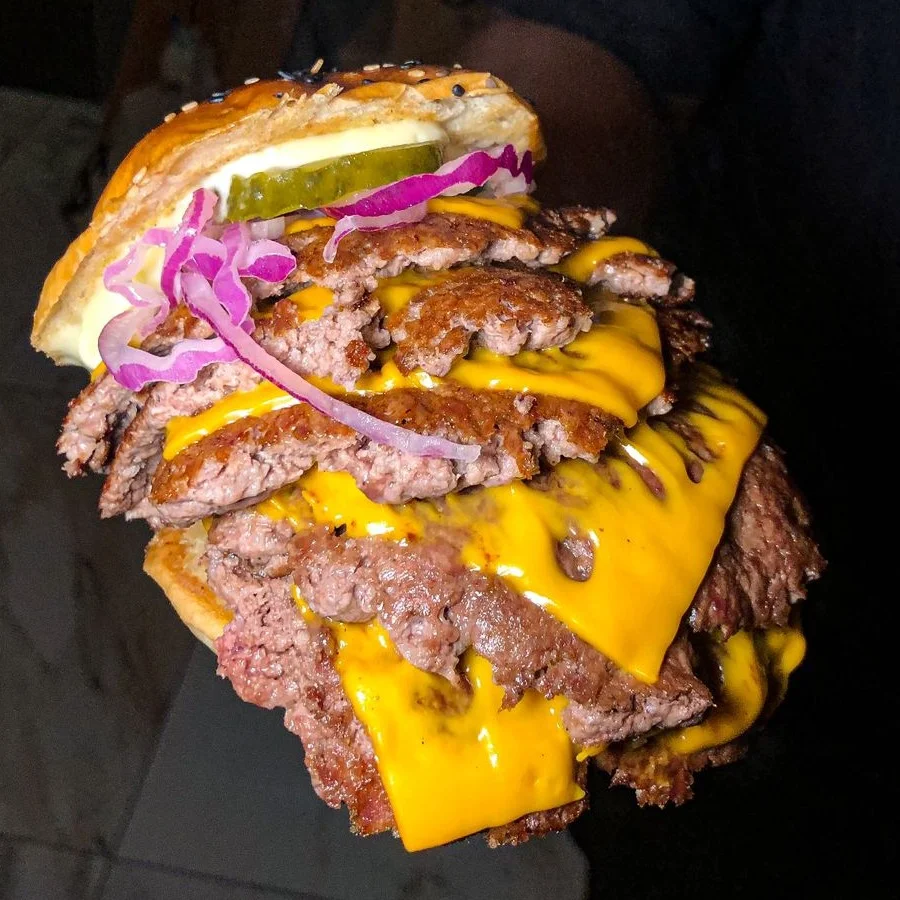 Hambúrguer artesanal servido em close com molho e vegetais
